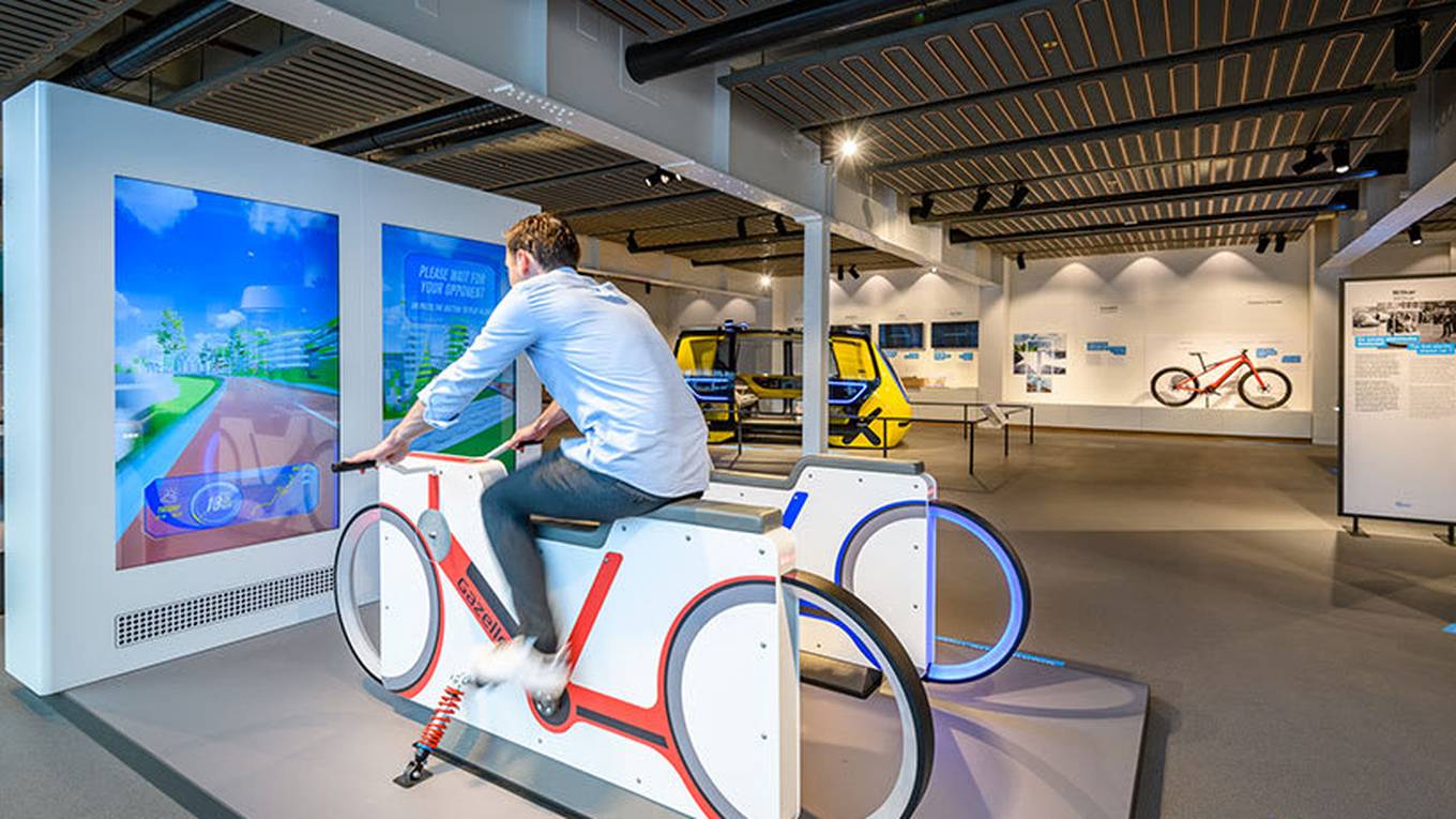 Een man zit binnen op een fiets voor een scherm met een simulatie