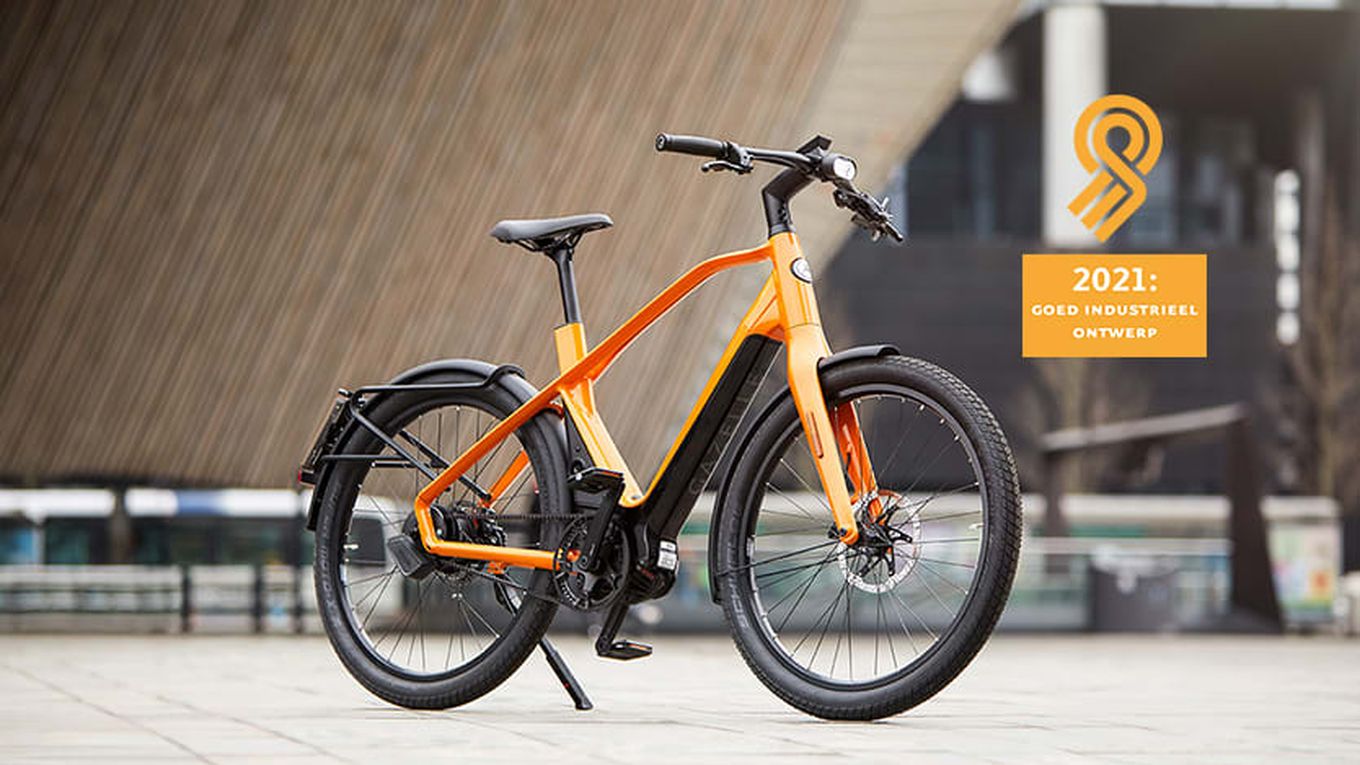 Een oranje fiets staat voor een gebouw met een oranje logo ernaast
